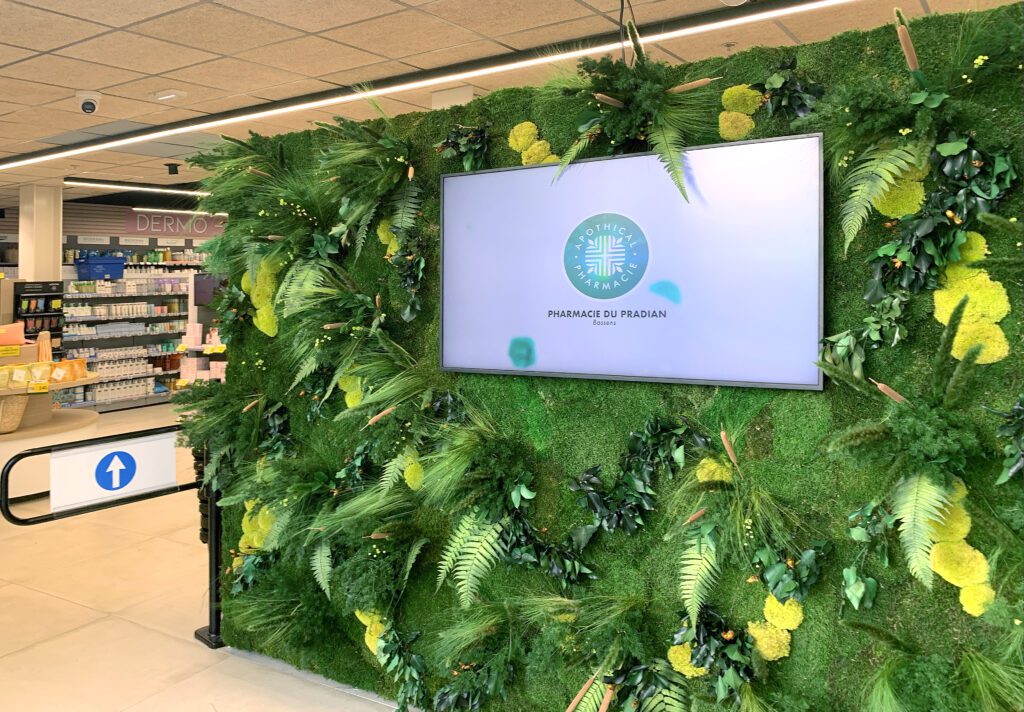Ecran digital sur mur vegetalisé à l'entrée de la pharmacie